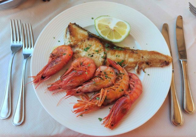 Piatto con gamberi, pesce grigliato e mezzo limone.