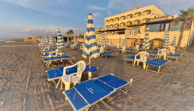 Spiaggia con lettini e ombrelloni blu e bianchi.