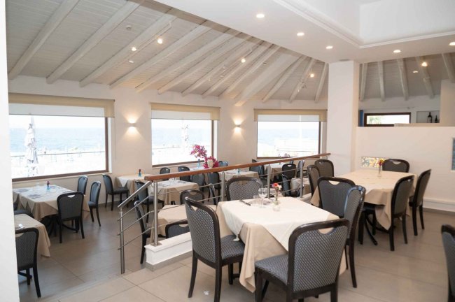 Sala ristorante con tavoli apparecchiati e finestre panoramiche.