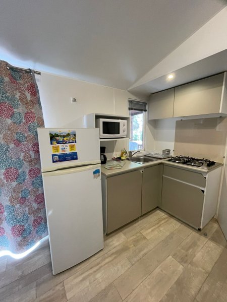Cucina compatta con frigorifero, microonde e fornelli a gas.