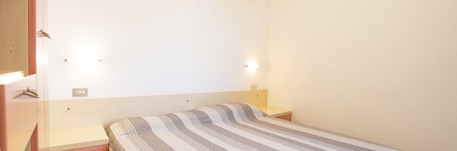 Camera con letto matrimoniale e pareti bianche.