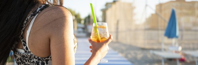 Persona tiene bicchiere con bevanda alla spiaggia.