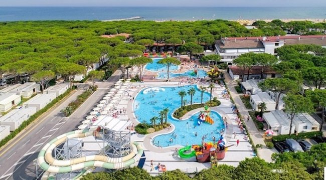Vista aerea di un parco acquatico con piscine e scivoli, vicino al mare.
