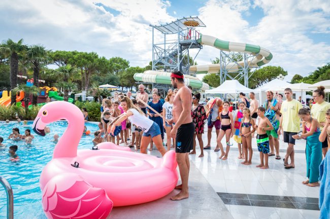 Persone in piscina con un gonfiabile a forma di fenicottero rosa.
