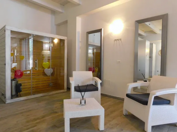 Stanza con sauna, poltrone bianche e tavolino.