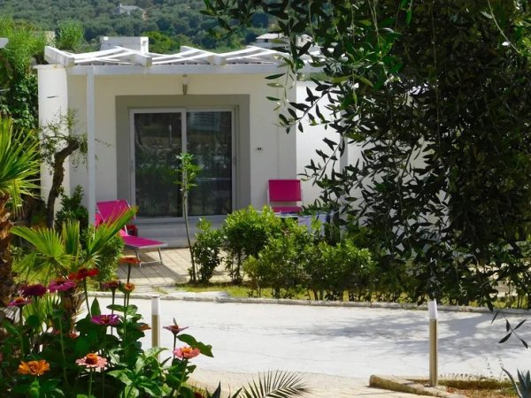 Casa bianca con giardino e piante fiorite.