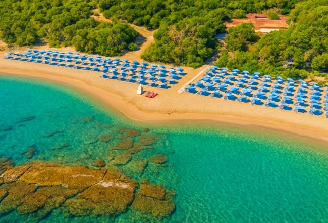 Spiaggia con ombrelloni blu e mare cristallino.