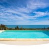Piscina con vista mare sotto un cielo azzurro.