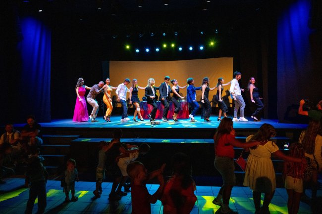 Persone ballano su un palco illuminato.