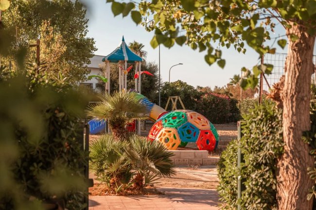 Parco giochi colorato tra alberi e piante.