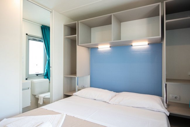 Camera da letto moderna con luce blu e bagno.