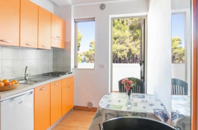 Cucina arancione con tavolo vicino alla finestra.