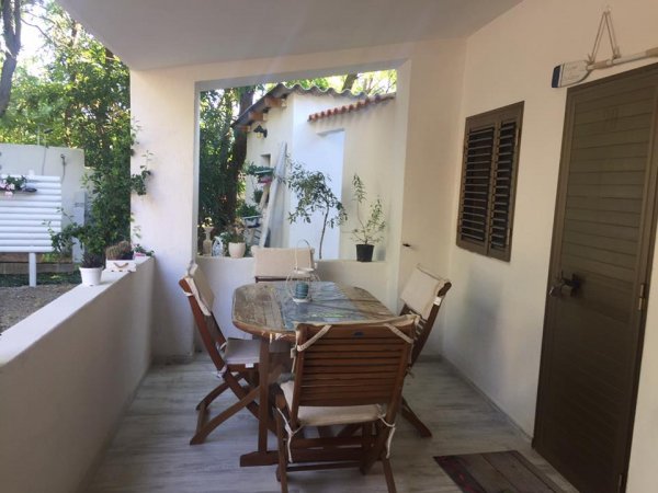 Una terrazza con tavolo e sedie in legno, circondata da piante.