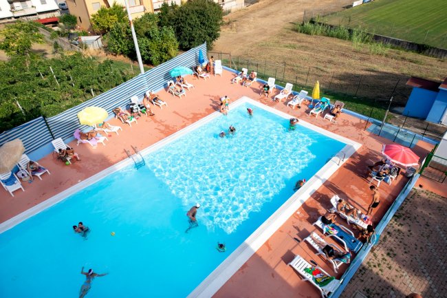 Persone in piscina e lettini attorno.
