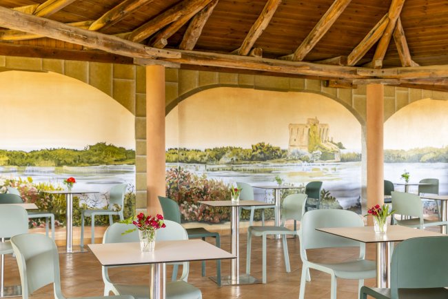 Sala interna con tavoli e murale di paesaggio.