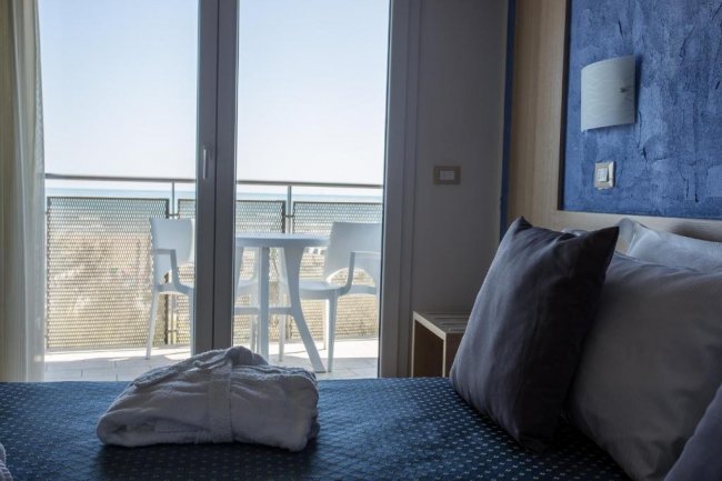 Camera d'albergo con vista mare e balcone.