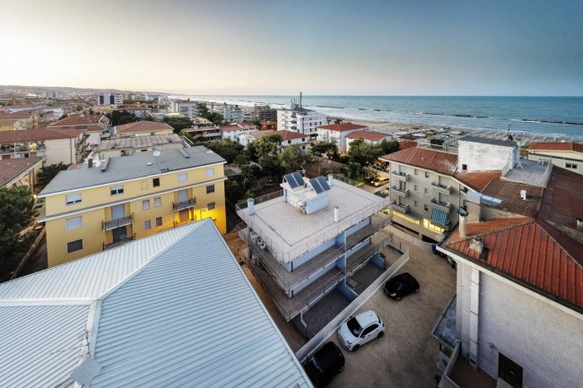 Vista dall'alto di edifici e mare al tramonto.