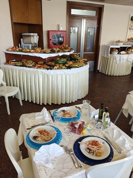 Sala da pranzo con tavolo preparato, buffet sullo sfondo.