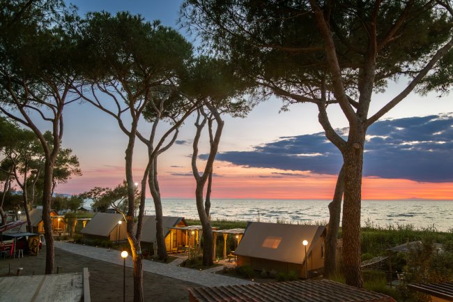 Bungalow tra alberi al tramonto sul mare.
