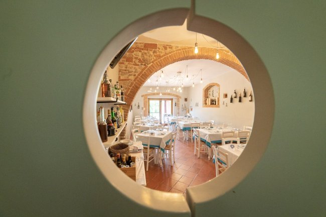 Sala da pranzo vista attraverso un pannello rotondo, con tavoli apparecchiati.