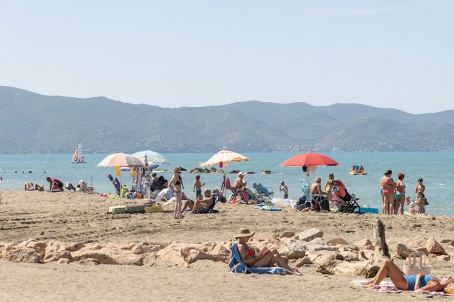 Spiaggia con persone, ombrelloni e mare azzurro sullo sfondo.