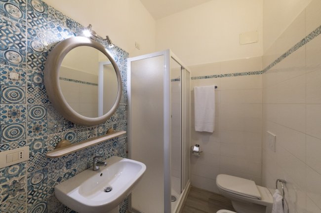 Bagno con specchio rotondo e doccia.