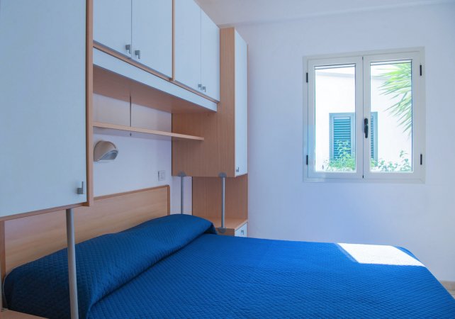 Camera con letto matrimoniale e finestre aperte.