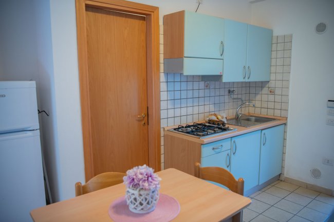 Cucina con mobili azzurri e tavolo in legno.