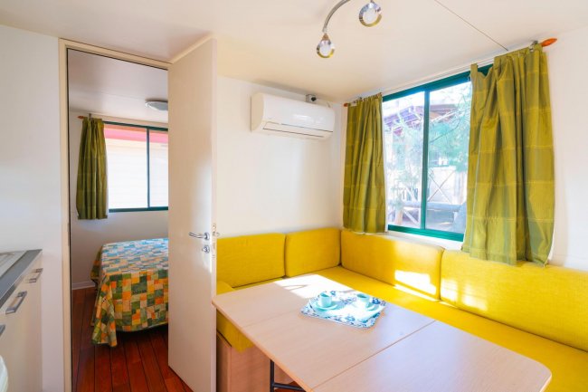 Interno mobile home con divano giallo e tavolo.