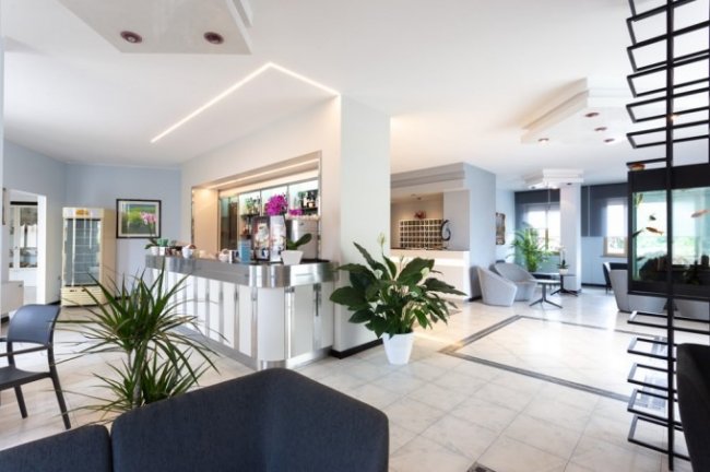 Reception moderna con piante e sedute eleganti.