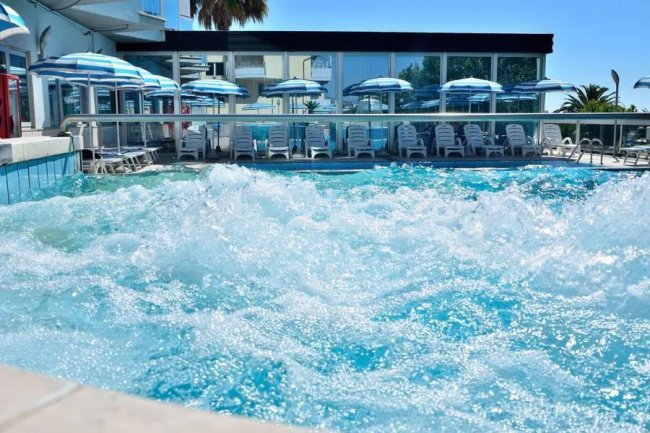 Piscina con idromassaggio e ombrelloni azzurri.