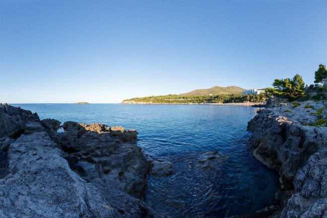 Costa rocciosa con mare blu e cielo limpido.