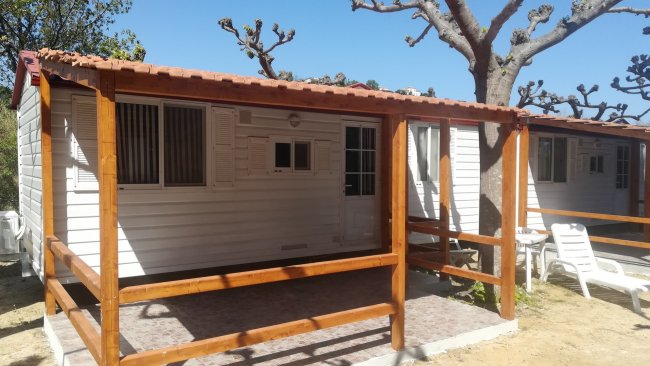 Bungalow bianco con veranda in legno.