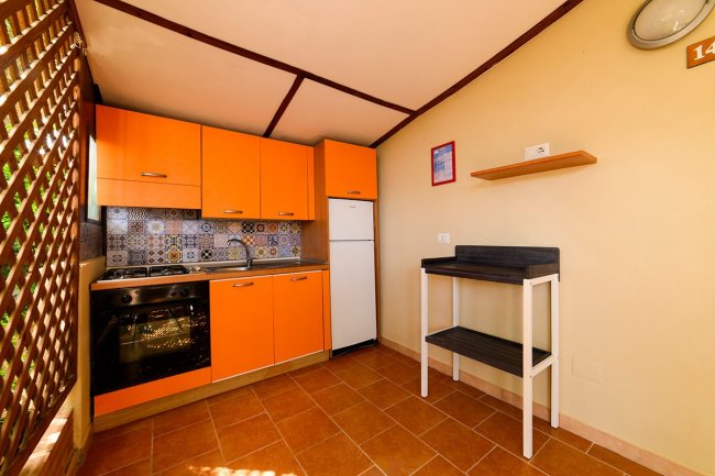 Cucina con mobili arancioni e piastrelle colorate.