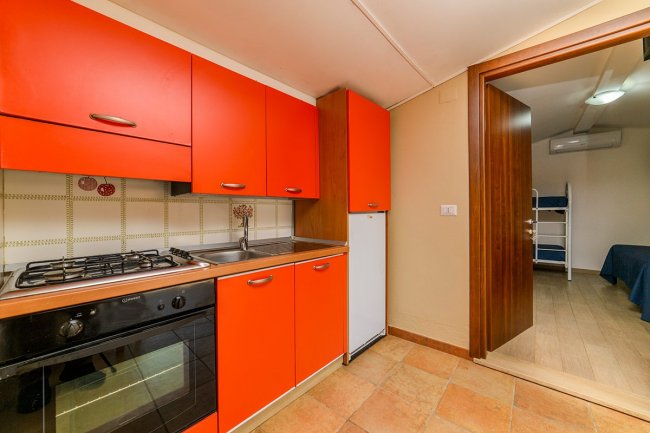 Cucina con mobili rossi, forno e frigorifero.