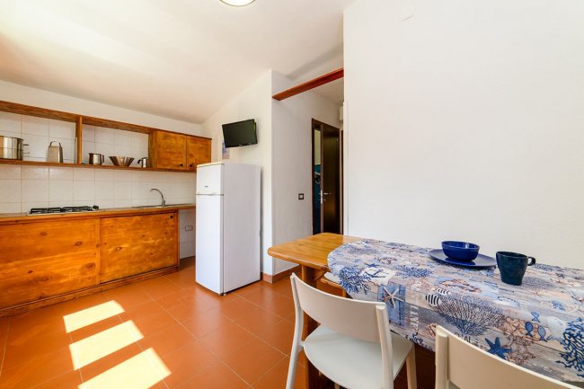 Cucina con mobili in legno e tavolo apparecchiato.