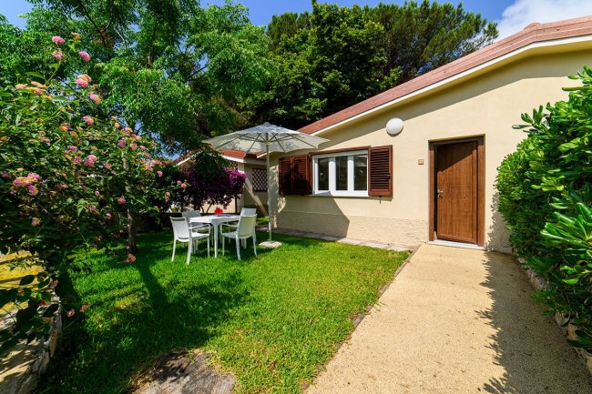 Giardino con tavolo, sedie e ombrellone vicino a una casa.