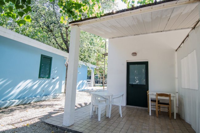 Veranda con tavolo e sedie bianche accanto a un edificio blu.