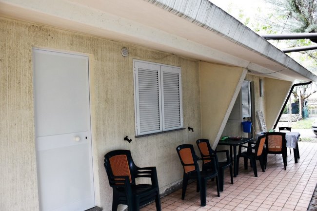 Esterno di una casa con sedie nere.