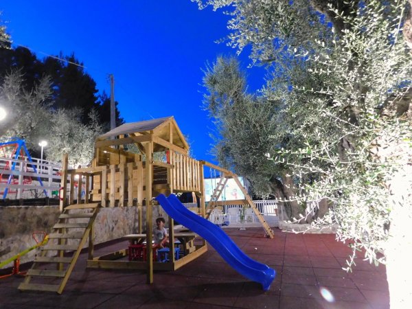 Parco giochi con scivolo blu e piattaforma in legno.