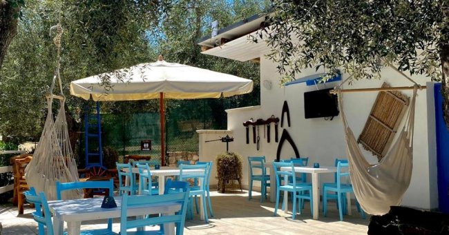 Patio con tavoli, sedie blu e amache.