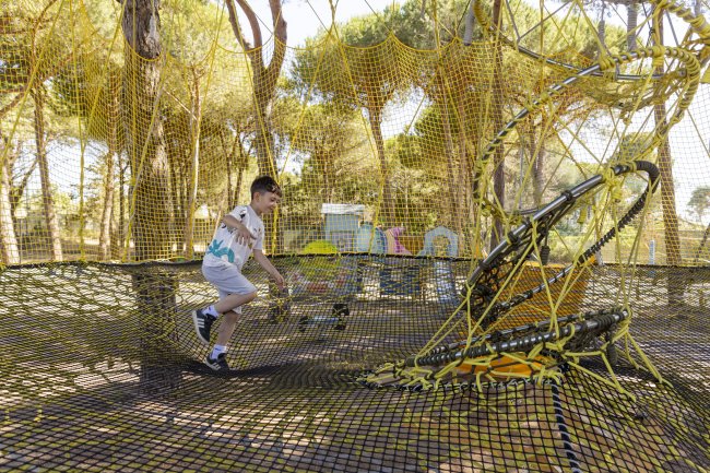 Ragazzo cammina su una rete in un parco avventura.