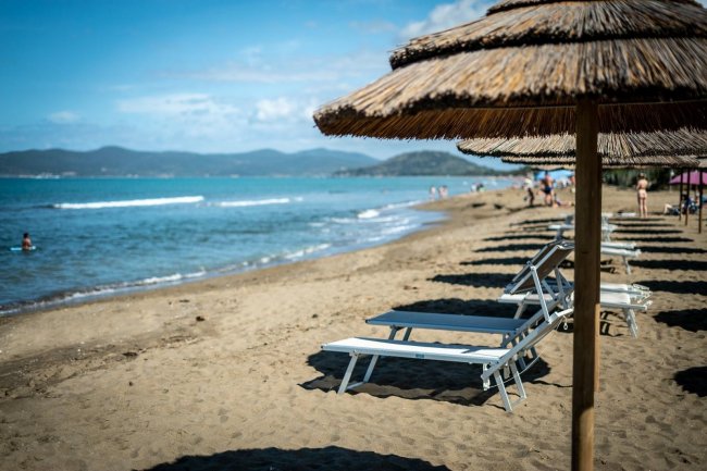 Spiaggia con lettini e ombrelloni in paglia.