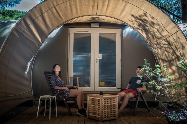 Due persone sedute davanti a una tenda glamping.
