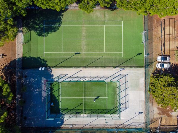 Vista aerea di campi da tennis verdi e recintati.