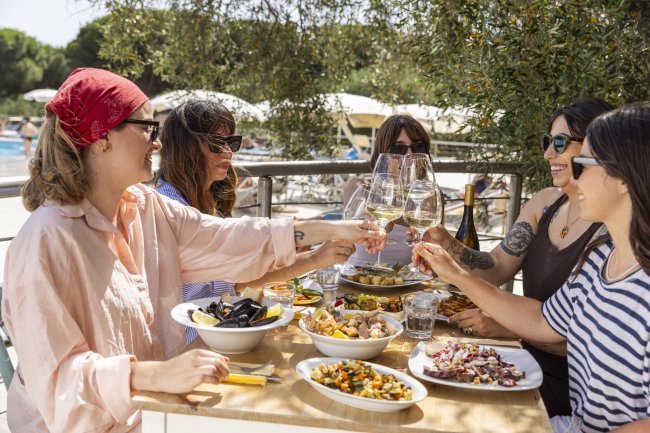 Gruppo di persone brinda all'aperto con cibo su un tavolo.