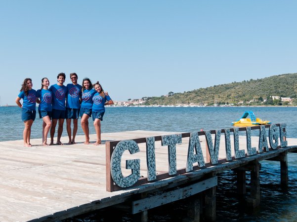 Gruppo sul molo con sfondo mare e scritta 