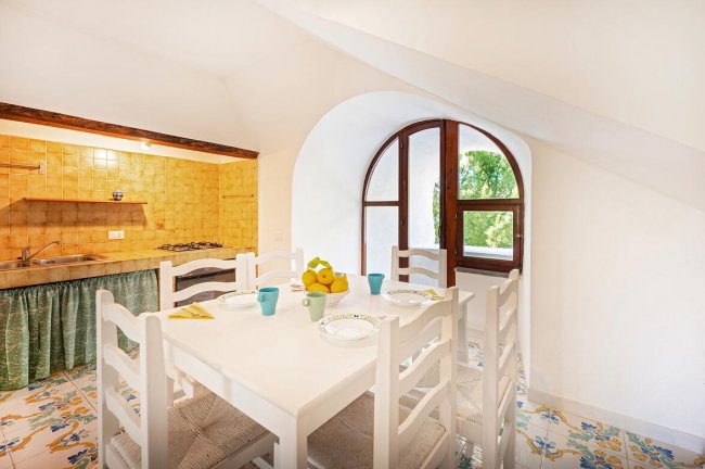 Sala da pranzo luminosa con tavolo bianco e sedie.