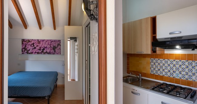 Vista parziale di cucina e camera con letto.