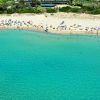 Spiaggia sabbiosa con bagnanti e acqua turchese.